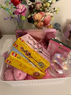 a basket filled with lots of different items on top of a white table next to flowers