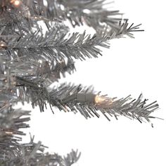 silver tinsel christmas tree with white lights on it's branches against a white background