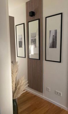 an empty hallway with pictures on the wall and a vase full of flowers in it