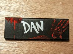 a wooden table with a black and red sign that says dan on it's side