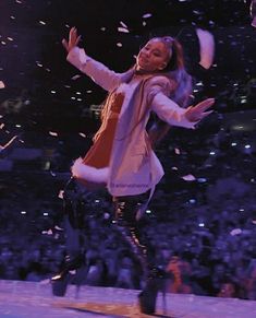 a woman dressed as santa clause dancing on stage with confetti in the air