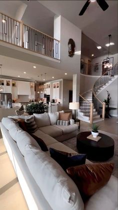 a living room filled with lots of furniture and a stair case in front of it