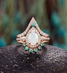 an opal and diamond ring on top of a rock