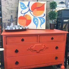 an orange dresser with some art on top