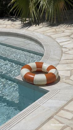 an orange and white life preserver sitting on the edge of a swimming pool