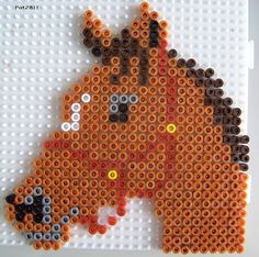 a horse made out of legos on a white board with orange and black dots