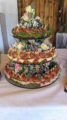 three tiered platter display with flowers and meats on each side, in front of a wooden wall