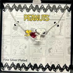 a peanuts necklace with a heart on it in a black box that says peanuts fine silver plated