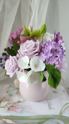 a pink vase filled with lots of purple and white flowers on top of a table