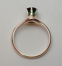 This is a 1940s-1950s classic! This is a six prong solitaire ring that has a 5.50 mm round synthetic (man made) green stone for the birth month of May. The stone has a fancy faceted top, similar to a rose cut on the top but with a pavilion like a modern cut round stone. There are some abrasions around the girdle, but the ring looks brand new other than that! The ring is stamped 10 kt and weighs 2.9 grams. Ring is sie 6.z Timeless Green Round Band Jewelry, Modern Green Jewelry With Prong Setting, Classic Emerald Ring With Bezel Setting For Anniversary, Classic Emerald Ring With Bezel Setting, Modern Emerald Jewelry With Center Stone, Elegant Bezel-set Emerald Ring For May Birthstone, Elegant Emerald Ring With Bezel Setting, 14k Gold Emerald Solitaire Ring With Round Cut, Heirloom Emerald Ring With Prong Setting For Formal Events