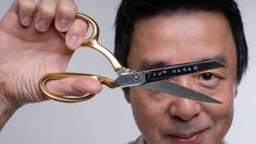 a man holding up a pair of scissors to his face