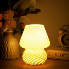 a white lamp sitting on top of a table next to a vase filled with flowers