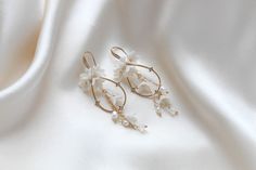 Our Irena teardrop Hoop Floral earrings for Bride are designed to be show stopping dangle hoops that will have everyone asking "where did you get those?!" Crafted with off white flower clusters & dangling freshwater pearls and white opal Austrian crystal beads, these earrings are perfect for casual or formal wear. - Handcrafted with genuine Austrian crystals- Created in my studio in PA- White opal crystals- Freshwater pearls- Polymer clay flowers- Yellow gold finish.- Earrings measure 3.25 inches x 1 inch- Handcrafted in the US.- Nickel free and hypoallergenic- PLEASE ALLOW APPROX 10 BUSINESS DAYS FOR COMPLETION BEFORE SHIPPING.This is an original design by © Treasures by Agnes Bridal Backdrops, Bridal Backdrop Necklace, Gold Bridal Hair Comb, Backdrops Necklace, Cubic Zirconia Bracelet, Crystal Bridal Earrings, Rose Gold Bridal, Freshwater Pearls Earrings, Cubic Zirconia Earrings