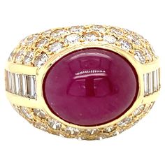 This ravishing 18K yellow gold ring from the 1970s centers a stunning 10-carat oval cabochon ruby, bezel-set and certified by GIA to have no indications of heat treatment, ensuring its natural beauty. The vibrant ruby is enhanced by an array of seventy straight baguette and round brilliant-cut diamonds totaling 3.45 carats, with G-H color and VS-2 clarity, adding a sleek and radiant sparkle. Measuring 16 mm wide and sitting 12 mm high on the finger when worn, this ring commands attention with it Cabochon Ruby, 18k Yellow Gold Ring, No Heat, Domed Ring, Ruby Diamond, Fine Jewelry Collection, Yellow Gold Ring, Oval Cabochon, Round Brilliant Cut Diamond