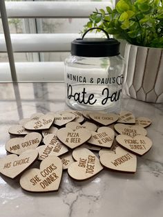 some wooden hearts are sitting on a table next to a glass jar and potted plant