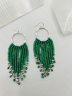 These fabulous beaded fringe earrings have a romantic boho chic vibe and are so light and easy to wear! Delicate strands of iridescent emerald green Czech glass seed beads cascade beautifully from silver coloured brass hoops. Handwoven with love by yours truly, each strand is completed with silver plated beads, Czech fire polished crystals   and a tiny hematite star charm adorns the centre strand.  The finished length of these earrings is approximately 3 inches (7.5cm) and 1.25 inches (3cm) across. The ear wires are silver plated and nickel free.  This listing is for one pair of earrings only. The video showing multiple pieces are for display purposes only. The additional earrings are also available in my shop under separate listings. These earrings would make a wonderful gift for someone Bohemian Green Chandelier Earrings For Festival, Handmade Green Tassel Earrings For Festival, Green Dangle Chandelier Earrings For Festival, Nickel Free Green Bohemian Chandelier Earrings, Green Chandelier Earrings With Dangling Beads For Festivals, Green Bohemian Chandelier Earrings Nickel Free, Green Nickel-free Bohemian Chandelier Earrings, Green Bohemian Beaded Dangle Earrings, Green Beaded Bohemian Chandelier Earrings