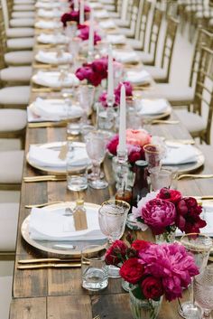 a long wooden table with white plates and pink flowers