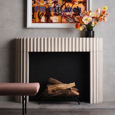 a fire place with a painting on the wall and flowers in vases next to it