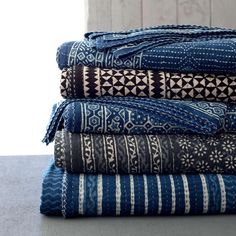 a stack of blue and white blankets sitting on top of a table next to a window