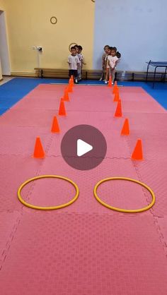 two children are playing with orange cones on the floor and one child is standing in front of them