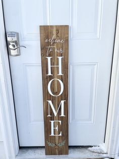 a wooden sign that says welcome to our home on the front door with wreaths