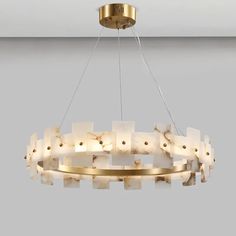 a chandelier made out of white marble blocks and gold metal fittings, suspended by a circular light fixture