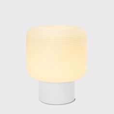 a white table lamp with a dim light on it's side and a round base