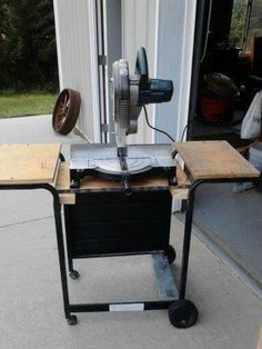 a table sawing machine sitting on top of a piece of wood next to a garage door