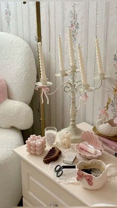 a white dresser topped with lots of pink and white items next to a teddy bear