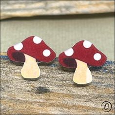 two red and white mushrooms sitting on top of a piece of wood with one mushroom sticking out of it's center