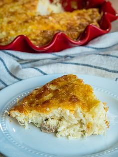 a piece of quiche on a plate next to a casserole dish with meat and cheese