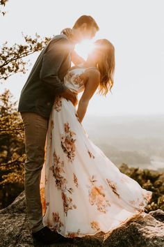 a bride and groom kissing on top of a mountain at sundown in the mountains