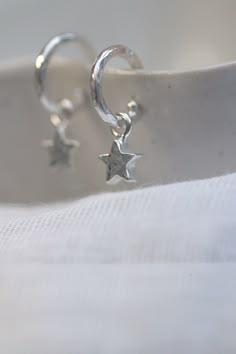 Small sterling silver huggie hoop earrings. Wear the Hoops alone or with the removable stars. This small hoop earring is close fitting and has a stud with butterfly closure. The dangles simply slide over the stud and slip round the earring without being able to come off.  Solid sterling silver is high quality and unless you have am allergy, a good option for sensitive ears. The silver is recycledand each earring and drop is handmade by me.  The hammered sterling silver catches the light beautifully and give these earrings their characterful handmade feel. They look very special indeed while still being practical enough for everyday wear.  The hoops measure approx 10mm diameter. Drop length approx 10mm. Choose from huggies with star dangles or plain huggies. Packaged beautifully ready to gi Cute Earring Studs, Two Earlobe Piercings, Pretty Silver Earrings, Huggie Hoop Earrings Silver, Jewellery Silver Earrings, Silver Hoops Small, Silver Star Huggie Earrings Minimalist Style, Silver Star-shaped Minimalist Huggie Earrings, Sterling Silver Star Huggie Earrings Minimalist Style