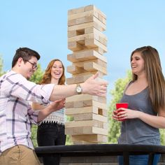 three people are playing with wooden blocks on a bench and one is holding a red cup