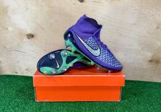 a pair of purple and green nike soccer cleats on top of an orange box