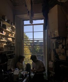 two people sitting at a table in front of a window with the sun shining through