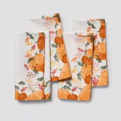 four napkins with pumpkins and leaves on them, one is folded in front of the other