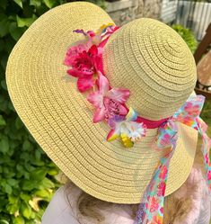 "Who's ready for the beach?  Do you have all the appropriate beach gear you'll need when summer rolls around?  How about a fun beach hat, more specifically, a fun beach hat that reminds you of being at a tropical island?  This woven straw sun hats has a wide, floppy brim and 22\" circumference to fit nearly all adults.  The sun hat is breathable and keeps the sun's glare at bay, making it perfectly comfortable to wear outdoors in the summer, gardening or hosting backyard parties. Use the floppy sun hat as table decor that guests can take with them!  Relax in style this summer by protecting your skin and looking fabulous.  An orchid-print and rainbow lace ribbons, bow and tropical orchids adding a wonderful touch! Start getting yourself beach ready with this adult floppy beach hat!" Tropical Hats Women, Pink Straw Sun Hat For Summer, Pink Straw Hat For Summer, Bucket Sun Hat With Uv Protection For Summer Activities, Adjustable Pink Straw Hat For Summer, Adjustable Pink Straw Sun Hat, Pink Straw Hat With Uv Protection For Beach, Adjustable Pink Straw Hat With Uv Protection, Brimmed Hats With Uv Protection For Summer