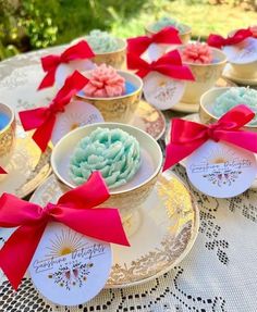 small cupcakes with red bows on them are sitting in gold cups and saucers