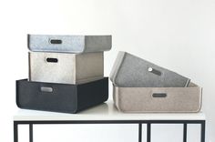 three storage bins sitting on top of a white table with black and grey handles