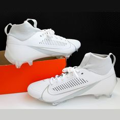 a pair of white soccer shoes sitting on top of a red and orange shoe box