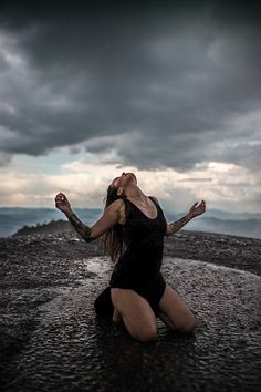 a woman sitting on the ground with her arms spread out in front of her head