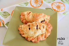 two pieces of pie on a green plate next to an orange and white napkin with leaves