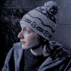 a woman wearing a white and black knitted hat looking off into the distance with her eyes closed