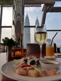 a white plate topped with food next to a glass of wine on top of a table