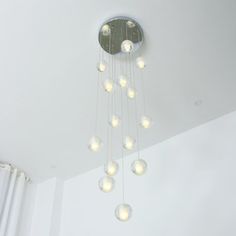 a chandelier hanging from the ceiling in a room with white walls and curtains