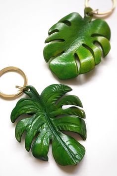 two green leaf shaped key chains on a white surface