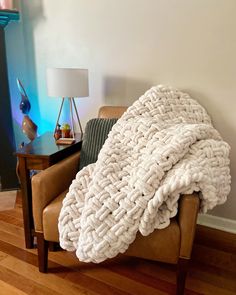 a couch with a blanket on top of it in a living room next to a lamp