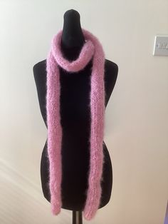 a pink knitted scarf sitting on top of a mannequin