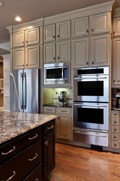 a kitchen with white cabinets and stainless steel ovens, refrigerator, microwave and dishwasher